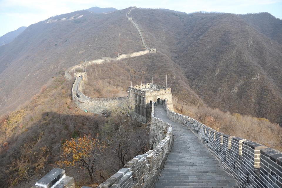 The Great Wall at Mutianyu runs from a stone watchtower along bare autumn ridges into the distance.