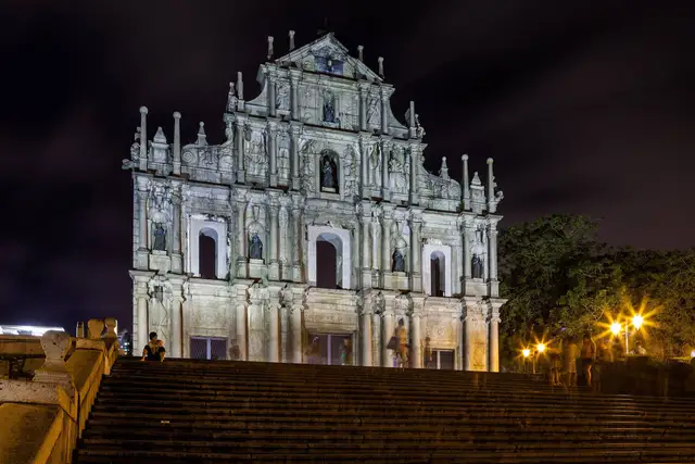 The floodlit stone façade of the Ruins of St. Paul's in Macao at night, seen from the foot of the grand stairway.