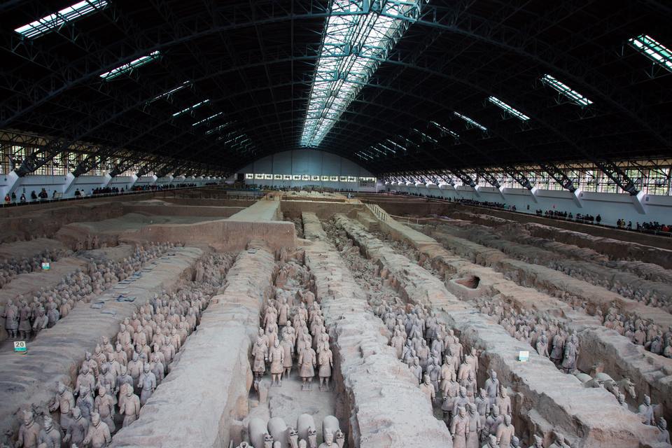 A wide view of Pit 1 of the Terracotta Army, with rows of clay warriors standing in long earthen trenches under the hall roof.